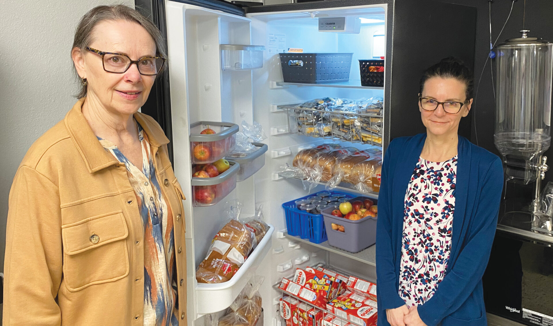 Corner Cupboard Food Bank upgraded East Elgin Secondary School’s “Nutrition Program Kitchen, two women stand in front of the new fridge they got because of the program